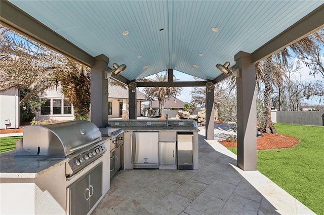 view of patio with exterior kitchen, a sink, grilling area, and fence