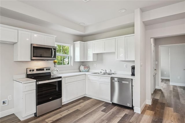 kitchen with appliances with stainless steel finishes, light countertops, white cabinets, and a sink