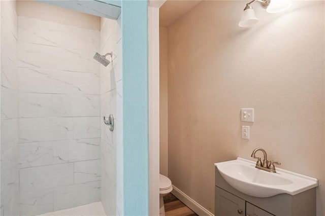 bathroom featuring a tile shower, vanity, and toilet