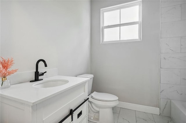 bathroom featuring a washtub, toilet, vanity, baseboards, and marble finish floor