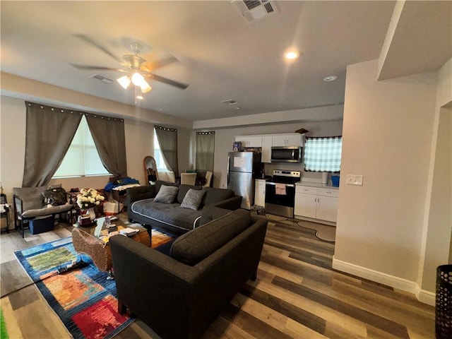 living room featuring dark wood-style floors, ceiling fan, visible vents, and baseboards