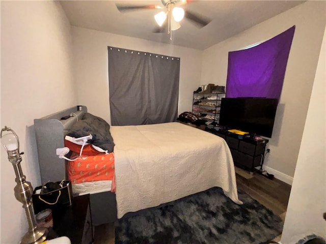 bedroom featuring ceiling fan, baseboards, and wood finished floors