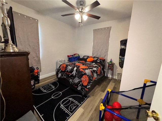 bedroom with a ceiling fan, baseboards, and wood finished floors