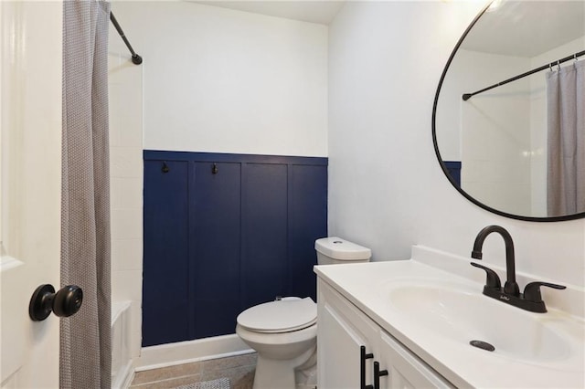 full bathroom with curtained shower, wainscoting, vanity, and toilet