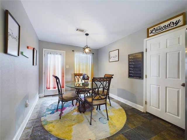 dining area featuring baseboards, visible vents, and stone tile floors