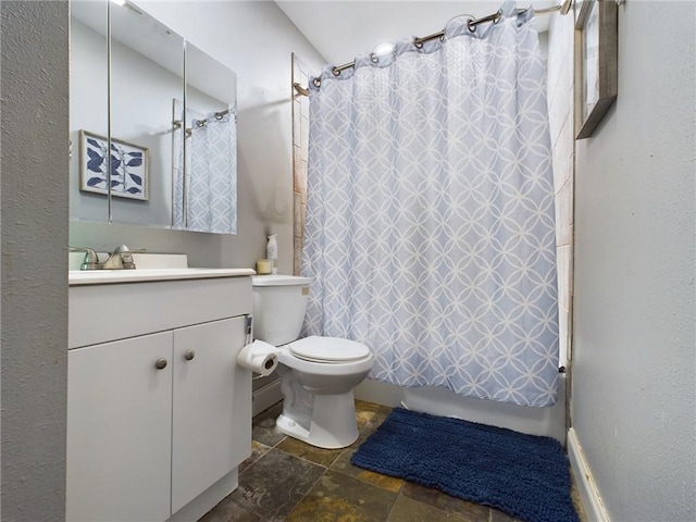 bathroom featuring toilet, shower / bath combo with shower curtain, stone tile flooring, and vanity