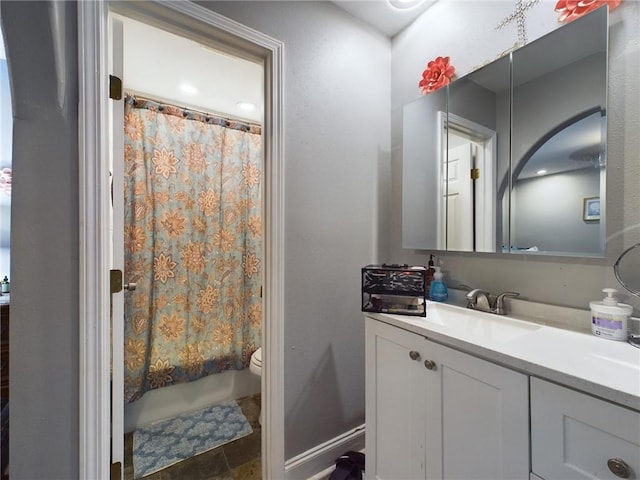 bathroom with stone finish floor, shower / bath combo with shower curtain, vanity, and toilet