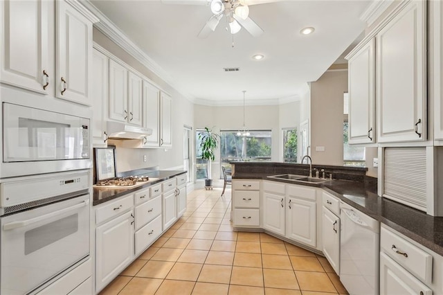 kitchen featuring under cabinet range hood, white appliances, white cabinets, and a sink