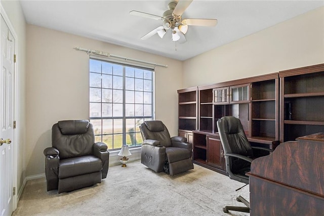 carpeted office space featuring baseboards and a ceiling fan