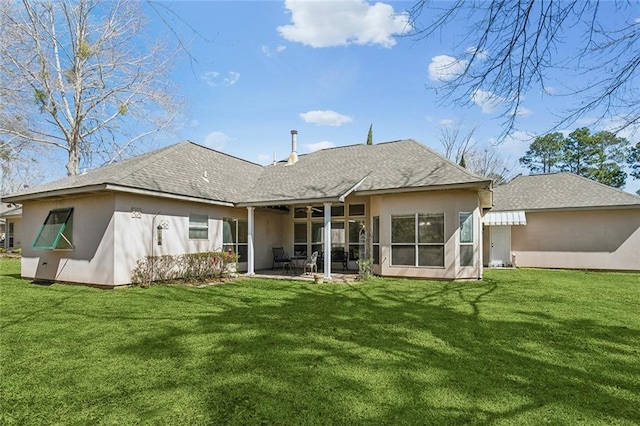 rear view of property with stucco siding, a yard, a shingled roof, and a patio area