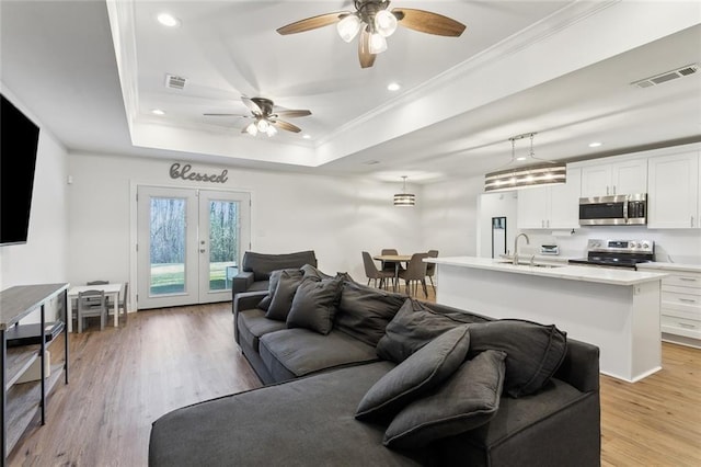 living area with a tray ceiling, visible vents, crown molding, and french doors