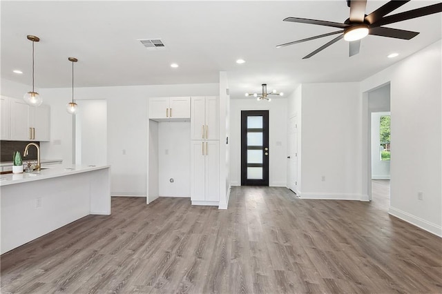 interior space with visible vents, white cabinets, light countertops, light wood-type flooring, and a sink