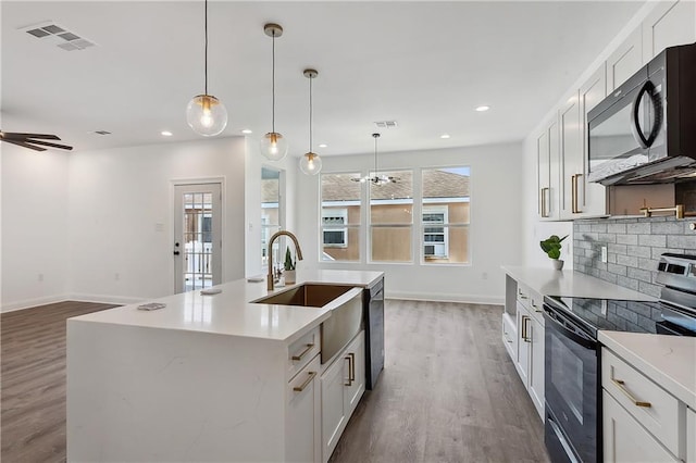 kitchen with black microwave, a sink, visible vents, electric stove, and tasteful backsplash