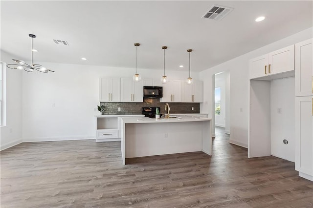 kitchen with white cabinetry, black appliances, tasteful backsplash, and visible vents