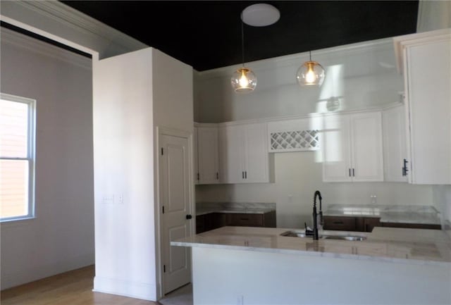 kitchen featuring a peninsula, white cabinetry, pendant lighting, and a sink