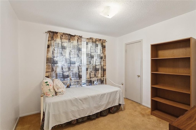 bedroom with light colored carpet, a textured ceiling, and baseboards