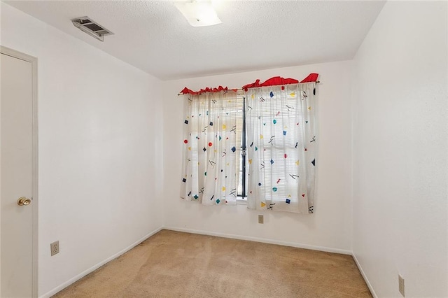 unfurnished room with baseboards, visible vents, a textured ceiling, and light colored carpet