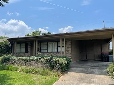 ranch-style house featuring a carport, concrete driveway, and brick siding