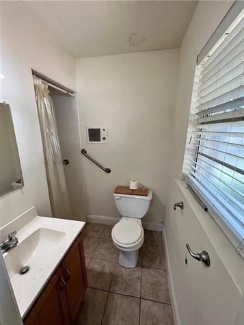 full bath with curtained shower, toilet, vanity, baseboards, and tile patterned floors