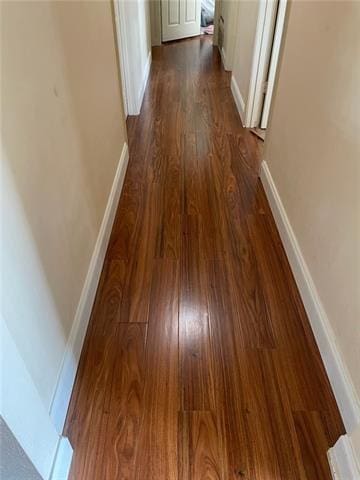 hallway with baseboards and dark wood-type flooring