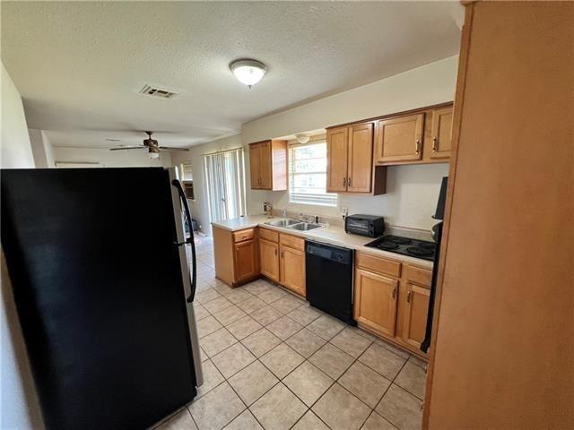 kitchen featuring visible vents, ceiling fan, light countertops, black appliances, and a sink