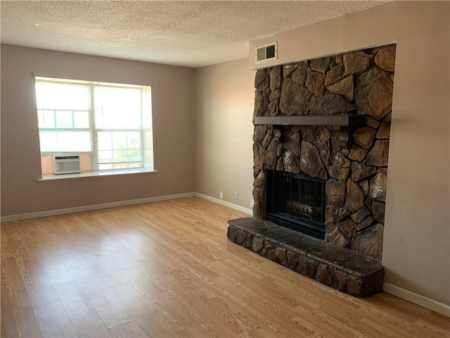 unfurnished living room with a fireplace, wood finished floors, visible vents, and baseboards