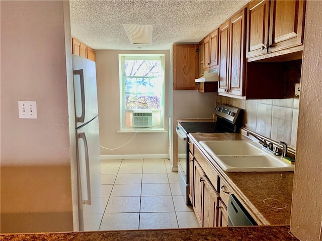 kitchen featuring light tile patterned floors, appliances with stainless steel finishes, brown cabinetry, a sink, and under cabinet range hood