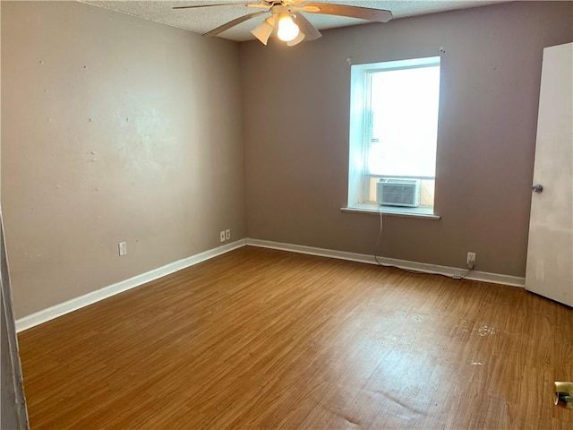 empty room featuring ceiling fan, a textured ceiling, wood finished floors, cooling unit, and baseboards