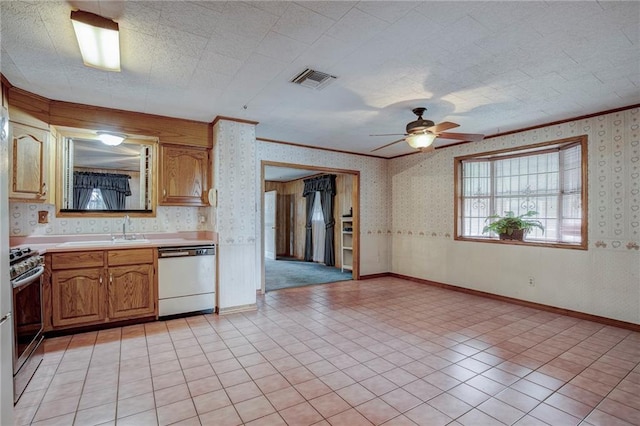 kitchen featuring dishwashing machine, wallpapered walls, stainless steel gas range, and light countertops