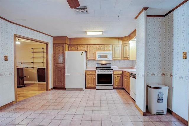 kitchen with white appliances, visible vents, light countertops, ornamental molding, and wallpapered walls