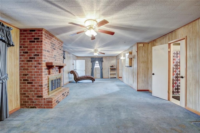 interior space with a textured ceiling, a fireplace, carpet flooring, and wooden walls