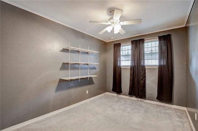 unfurnished room featuring carpet floors, ceiling fan, baseboards, and crown molding