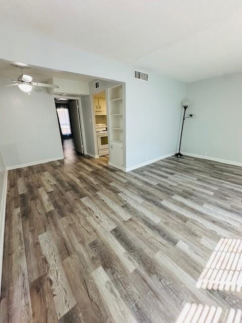 unfurnished living room with baseboards, visible vents, a ceiling fan, wood finished floors, and built in shelves