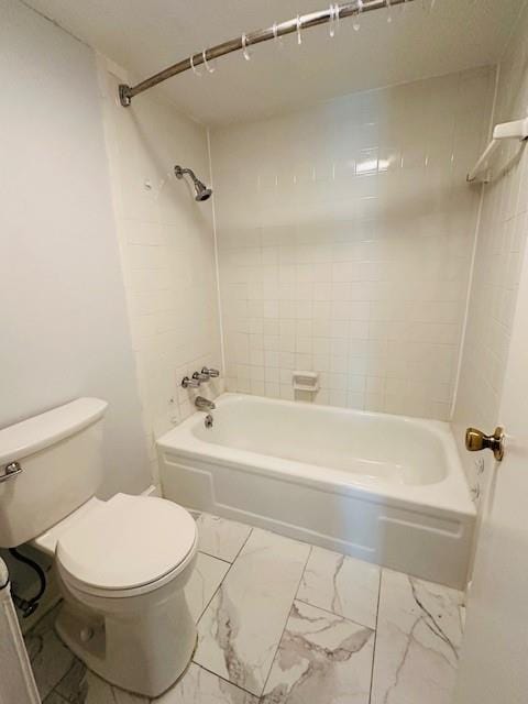 full bathroom with washtub / shower combination, marble finish floor, and toilet