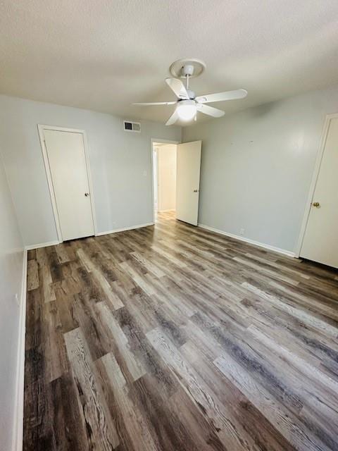 unfurnished room with a textured ceiling, wood finished floors, visible vents, and a ceiling fan