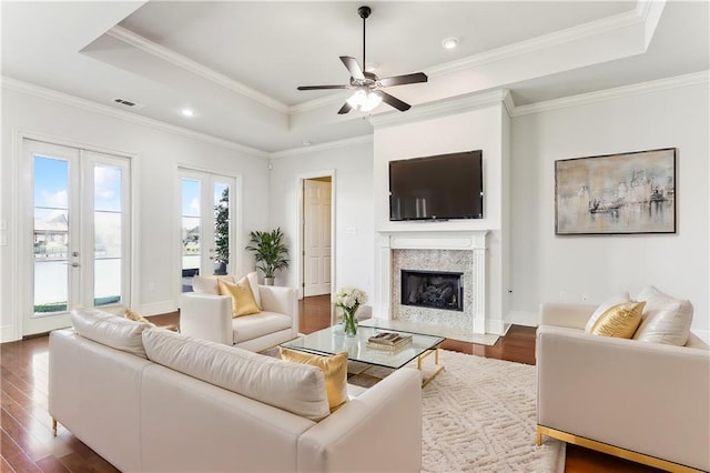 living room with dark wood-type flooring, a raised ceiling, visible vents, and crown molding