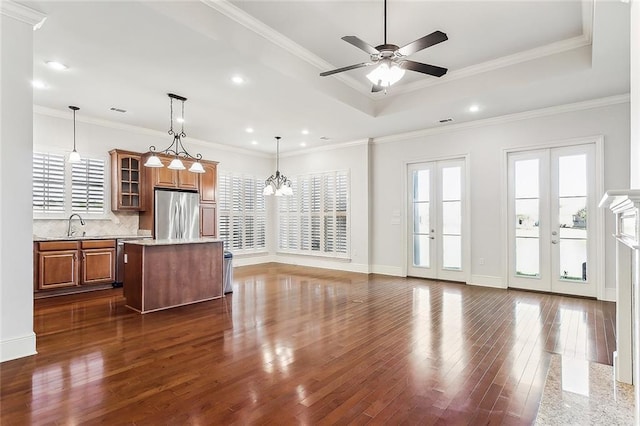 kitchen featuring dark wood-style floors, french doors, a raised ceiling, appliances with stainless steel finishes, and brown cabinetry