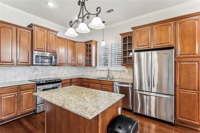 kitchen featuring visible vents, appliances with stainless steel finishes, glass insert cabinets, ornamental molding, and a sink