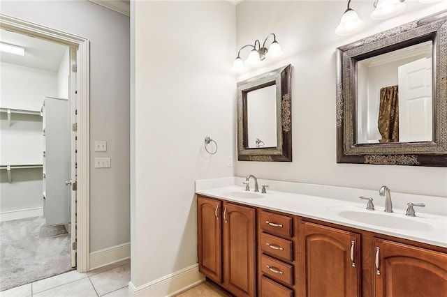 full bathroom featuring baseboards, double vanity, a sink, and tile patterned floors