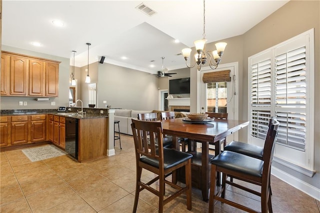 dining area featuring light tile patterned flooring, ceiling fan with notable chandelier, a fireplace, visible vents, and baseboards