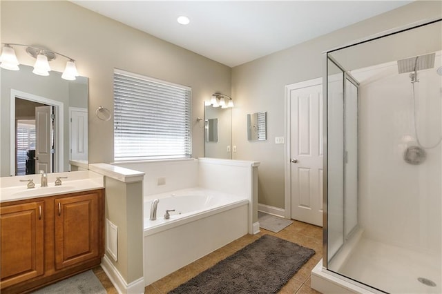 bathroom featuring a stall shower, tile patterned flooring, a garden tub, and vanity