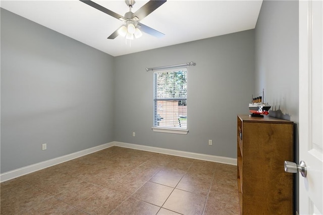 tiled spare room featuring ceiling fan and baseboards