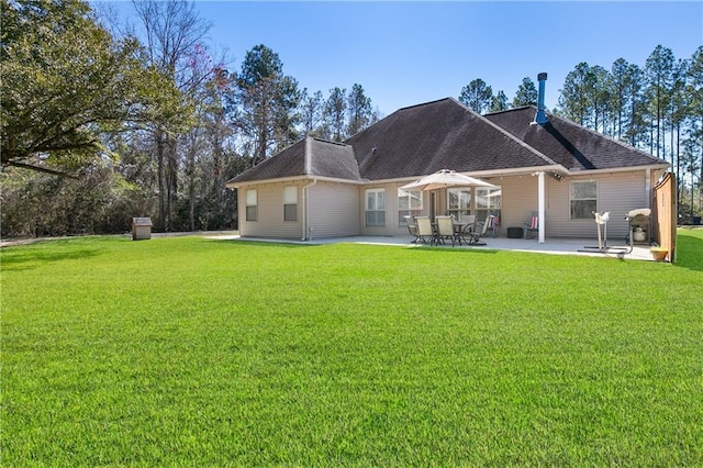 rear view of property featuring a patio, a lawn, and roof with shingles