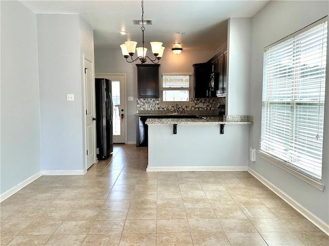 kitchen with a breakfast bar, visible vents, backsplash, a peninsula, and black fridge