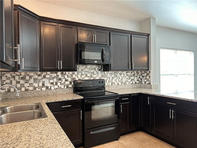 kitchen with light stone counters, light tile patterned floors, backsplash, a sink, and black appliances