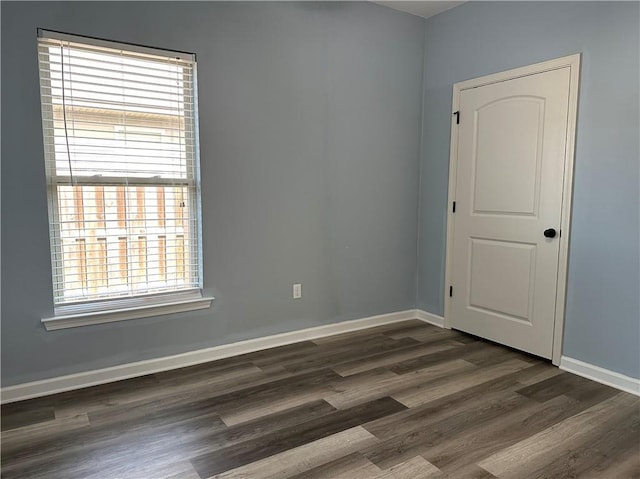 spare room featuring baseboards and wood finished floors