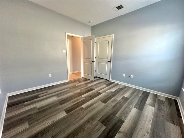 unfurnished bedroom featuring baseboards, visible vents, and wood finished floors