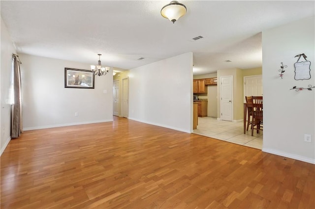 interior space featuring light wood finished floors, baseboards, visible vents, and an inviting chandelier