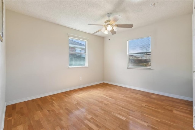 unfurnished room featuring a textured ceiling, light wood finished floors, and baseboards