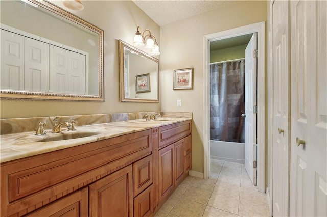 bathroom with double vanity, a sink, a textured ceiling, and tile patterned floors